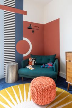 a living room with an orange, blue and white color scheme on the wall next to a green couch