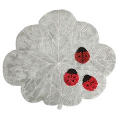 three red ladybugs on a white leaf shaped placemat with two black dots