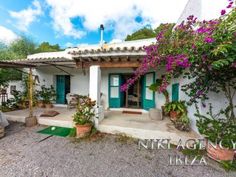 a white house with green shutters and purple flowers