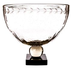 a clear glass bowl on a black stand with a white background in the back ground