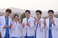 group of young men and women in white lab coats with their hands up to the camera