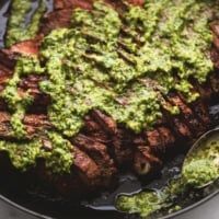 the steak is covered in green sauce and served with broccoli