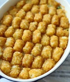 a white dish filled with tater tots on top of a table