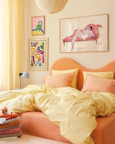 an orange bed with yellow sheets and pillows in a bedroom next to a painting on the wall