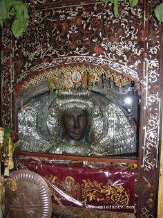 an ornately decorated shrine in the corner of a room with green leaves on it