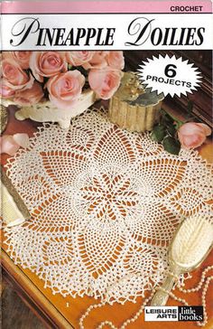 a crocheted doily is shown on a table with pink roses in the background