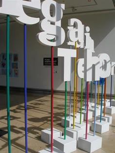 a group of colorful poles sitting in front of a white building with numbers on it