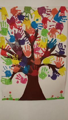 a tree made out of handprints on a white paper with red, green, blue and yellow hands