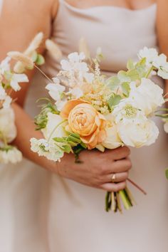 the bridesmaids are holding their bouquets with white and orange flowers on them