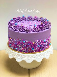 a cake with purple frosting and sprinkles sitting on top of a white plate