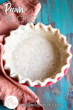 a pie crust sitting on top of a wooden table next to a pink napkin and bowl