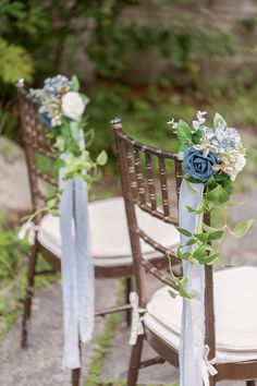 two chairs decorated with blue flowers and greenery are sitting on the ground next to each other