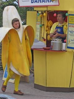 a man dressed as a banana standing in front of a stand