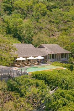 an aerial view of a resort with a pool surrounded by lush green trees and bushes