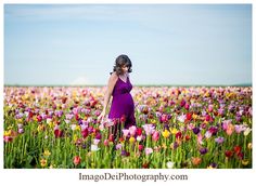 a pregnant woman standing in a field of flowers