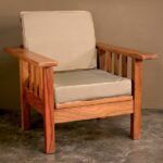 a wooden chair sitting in front of a wall with a white pillow on top of it