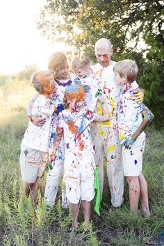 a group of people standing in the grass with paint all over their bodies and hands