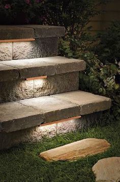 some steps lit up with lights in the grass and on top of them is a piece of wood