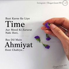 the hand is holding some purple flowers on top of a white paper with words written in different languages