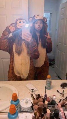 a woman taking a selfie in front of a mirror with three monkeys on her head