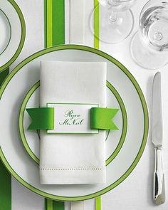 a place setting with green and white striped table cloths, napkins and silverware