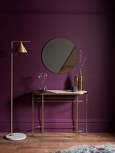 a table with a mirror and two wine glasses on it in front of a purple wall