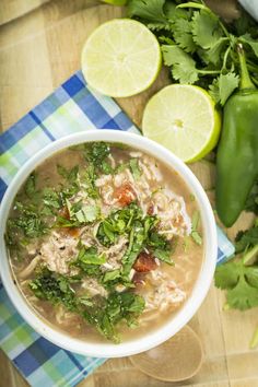 a bowl of chicken tortilla soup with cilantro and limes on the side