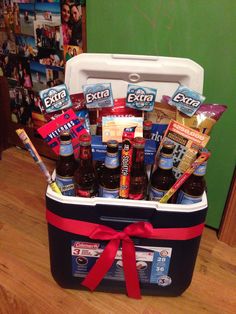 a cooler filled with beer and snacks on top of a wooden floor