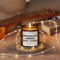 a lit candle sitting on top of a wooden table next to a string of lights