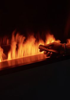 a hand holding something in front of a fire