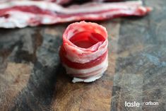 bacon wrapped in wax paper sitting on top of a wooden cutting board