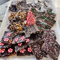 a white tray topped with lots of different types of cookies and candies on top of each other