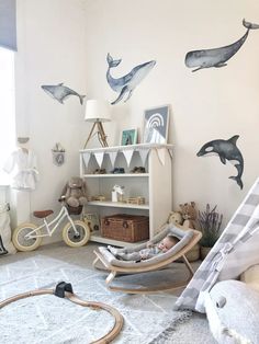 a child's room with dolphin decals on the wall and toys in rocking chairs