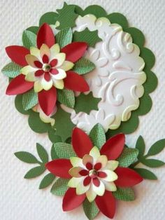 two paper poinsettis with green leaves and red flowers on white wallpaper