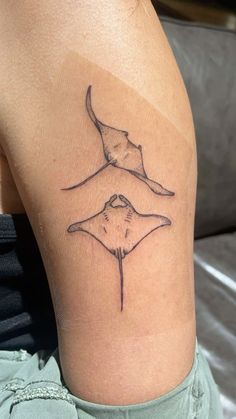 a woman with a tattoo on her lower leg shows the shape of a stingfish's tail