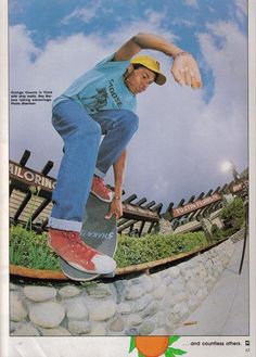 a man riding a skateboard down the side of a stone covered slope in front of a blue sky