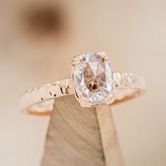 an engagement ring with a white diamond in the center on top of a piece of wood