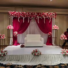 a white couch sitting on top of a bed covered in pink and white flowers next to a red curtain