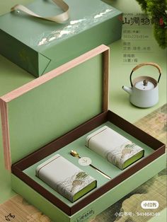 an open box with two tea bags in it on top of a table next to a pot