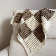 a crocheted blanket sitting on top of a white couch