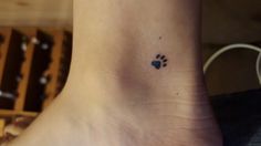 a small paw tattoo on the foot of a woman's left ankle, with a heart in it