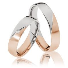 two white and rose gold wedding rings with diamond in the middle, set on top of each other