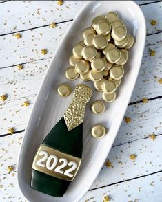 a white plate topped with lots of gold coins and a bottle of champagne next to it