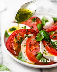 a white plate topped with tomatoes and mozzarella sauce being drizzled over it