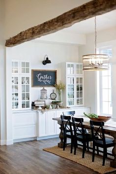 a dining room table with chairs and a chalkboard on the wall above it that says gather