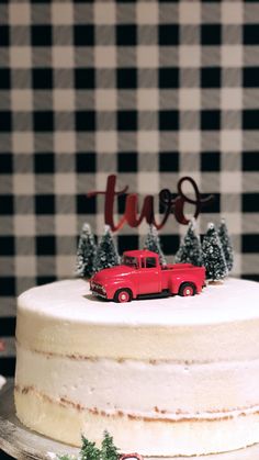 a red truck is parked on top of a white frosted cake with pine trees