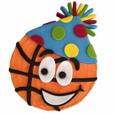 a birthday cake decorated like a basketball ball with a party hat on it's head