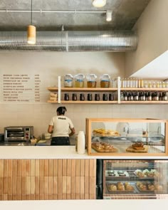 a person standing behind a counter in a bakery