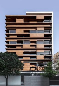 an apartment building with wooden slats on the side and trees in front of it