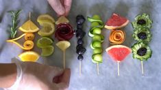 someone is making fruit skewers with different fruits and vegetables on the skewers